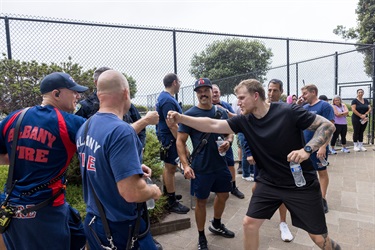 A firefighter and police officer in workout clothes fist bumping outside