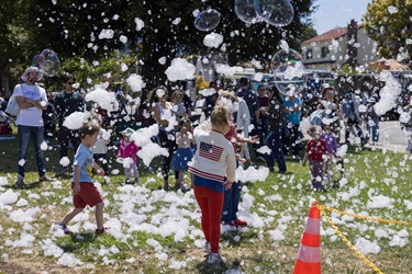 Kids playing in Memorial Park grass surrounded by bubbles