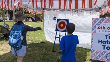 Person throwing toy hatchet at target for 4th of July carnival game