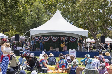 Musicians on stage under a tent playing in front of audience