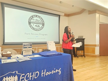 A person talking into a microphone presenting information at Homeowners & Tenants Resource Fair