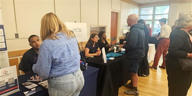 People talking to seated people at resource tables at Homeowners & Tenants Resource Fair